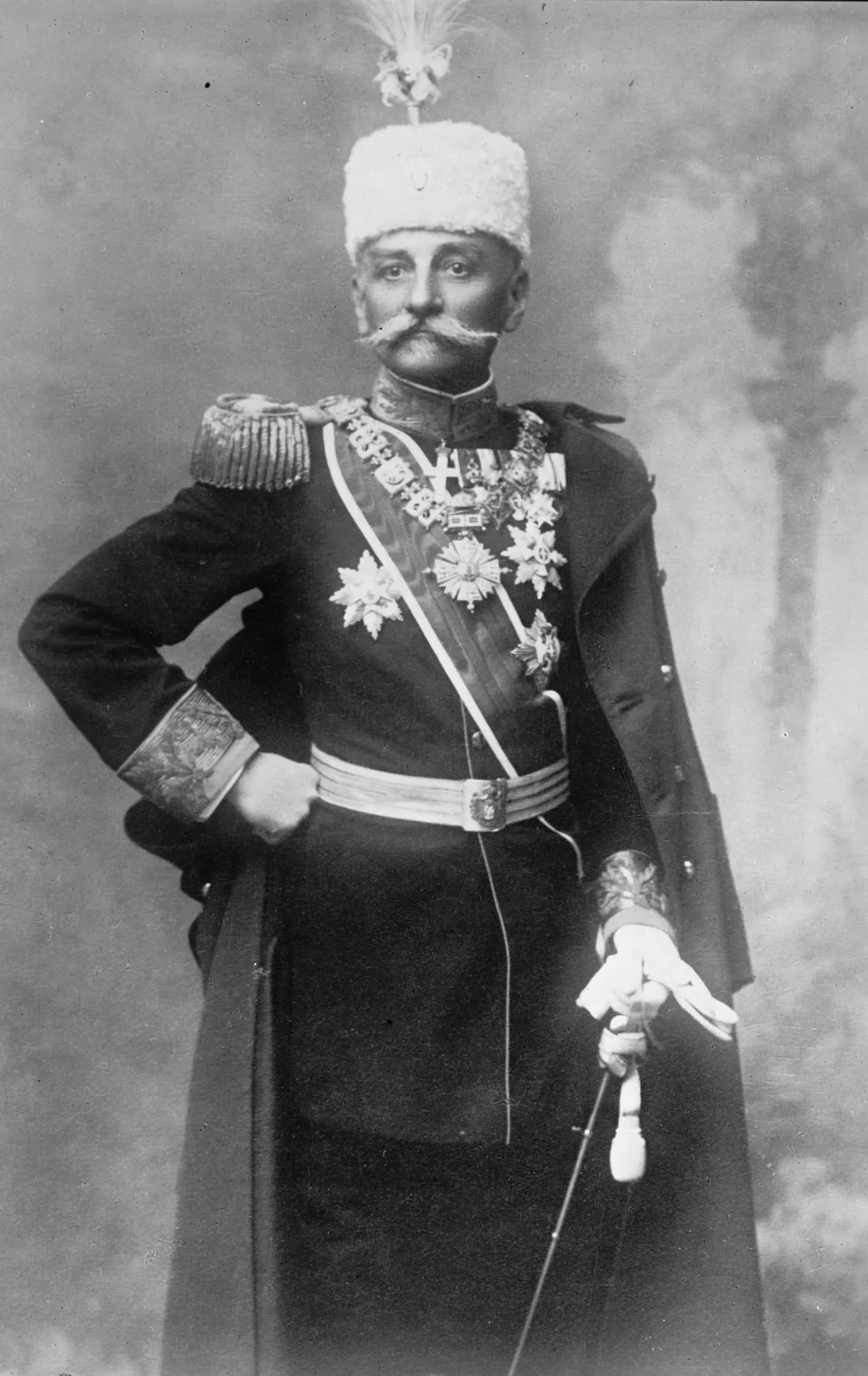 Formalna fotografija starijeg kralja sa sedom bradom u tamnoj uniformi sa epoletama.