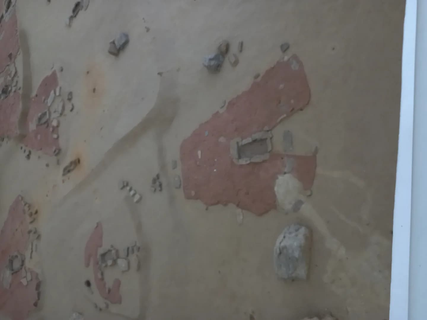 Rekonstrukcija trapezoidne praistorijske kuće sa kamenim podom i središnjim ognjištem.