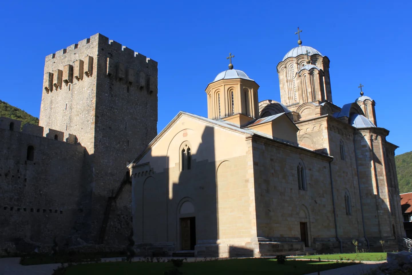 Srednjovekovna manastirska crkva iza visokih kamenih bedema sa odbrambenim kulama.