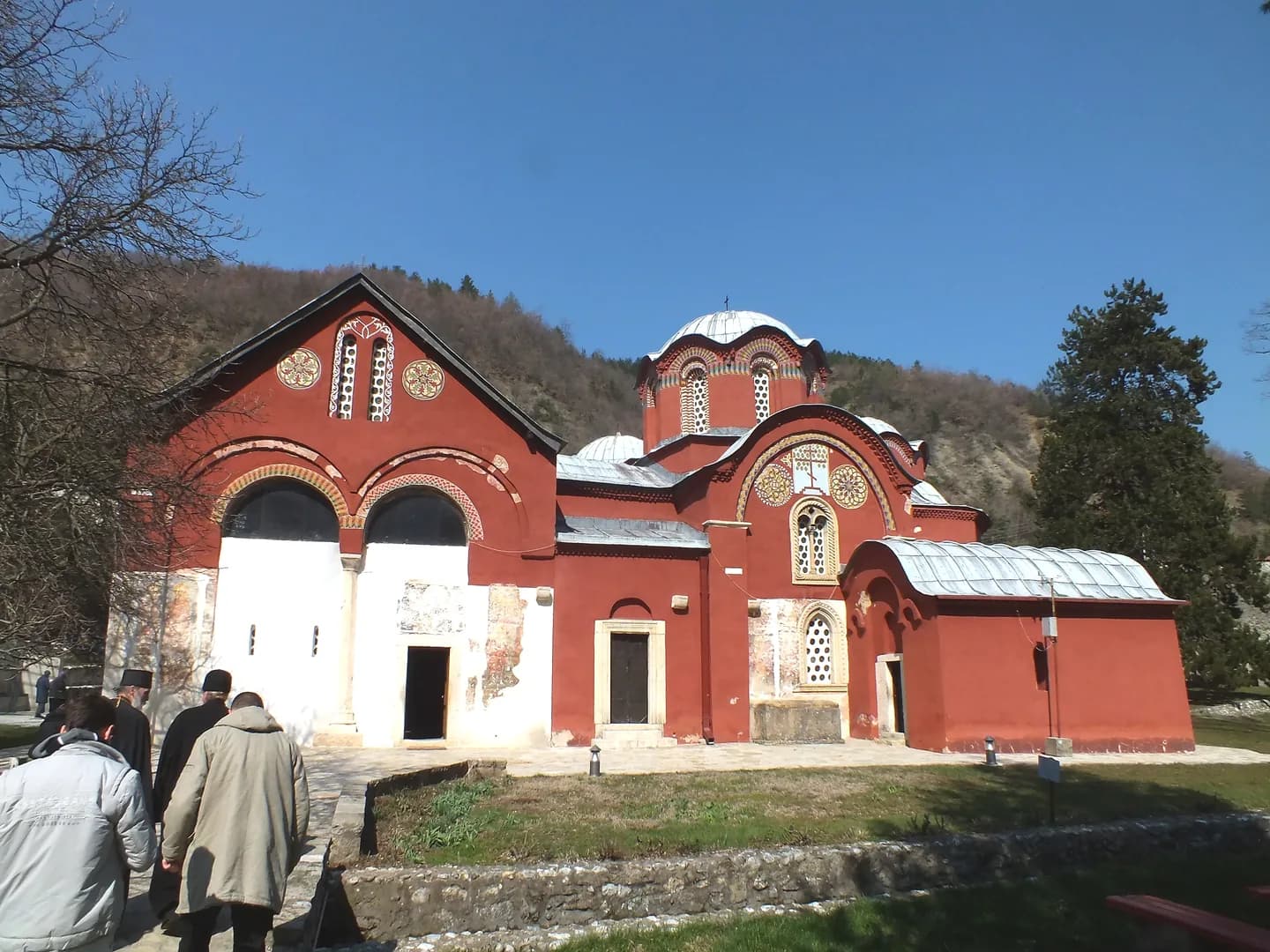 Kompleks od više povezanih srpskih srednjovekovnih crkava sa crvenim krovovima u podnožju planine.